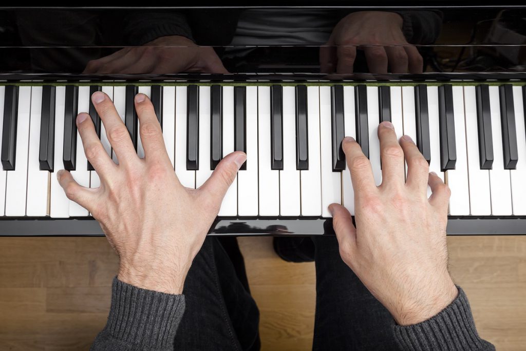 Pianino - widok z góry na ręce grające na pianinie