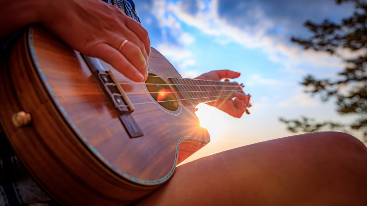 Osoba grająca na ukulele o zachodzie słońca