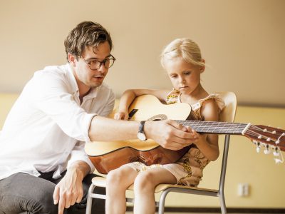 Mężczyzna uczący dziewczynkę gry na gitarze