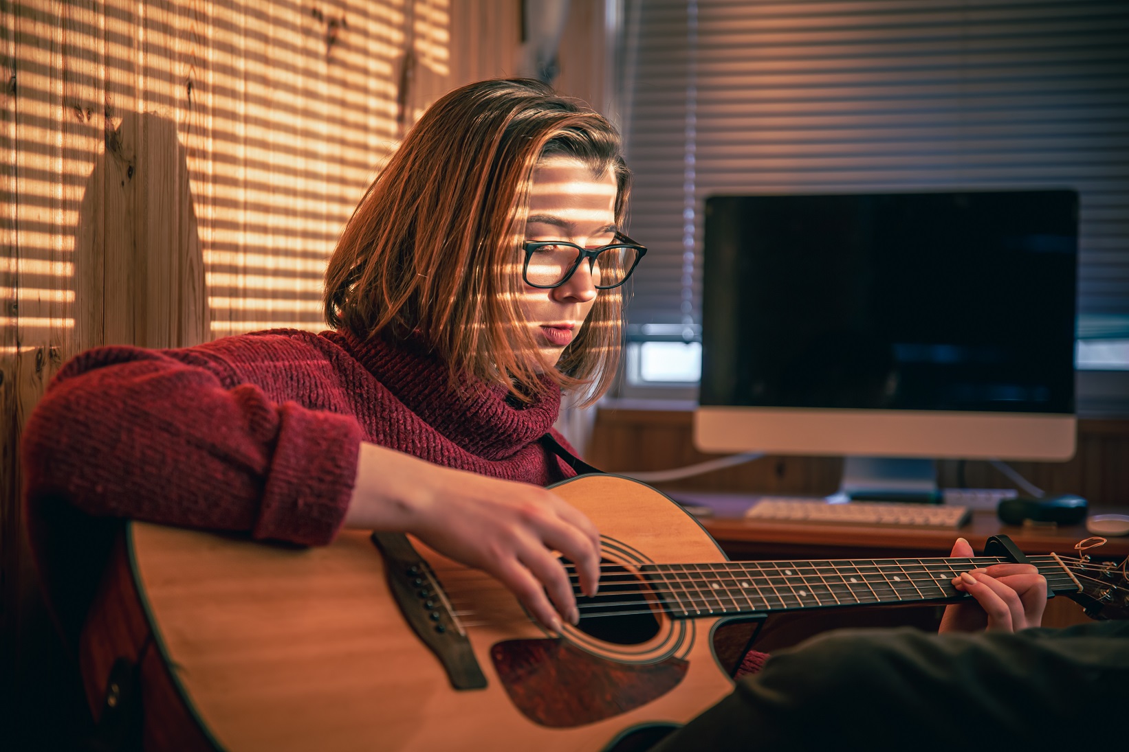 Kobieta w okularach grająca na gitarze