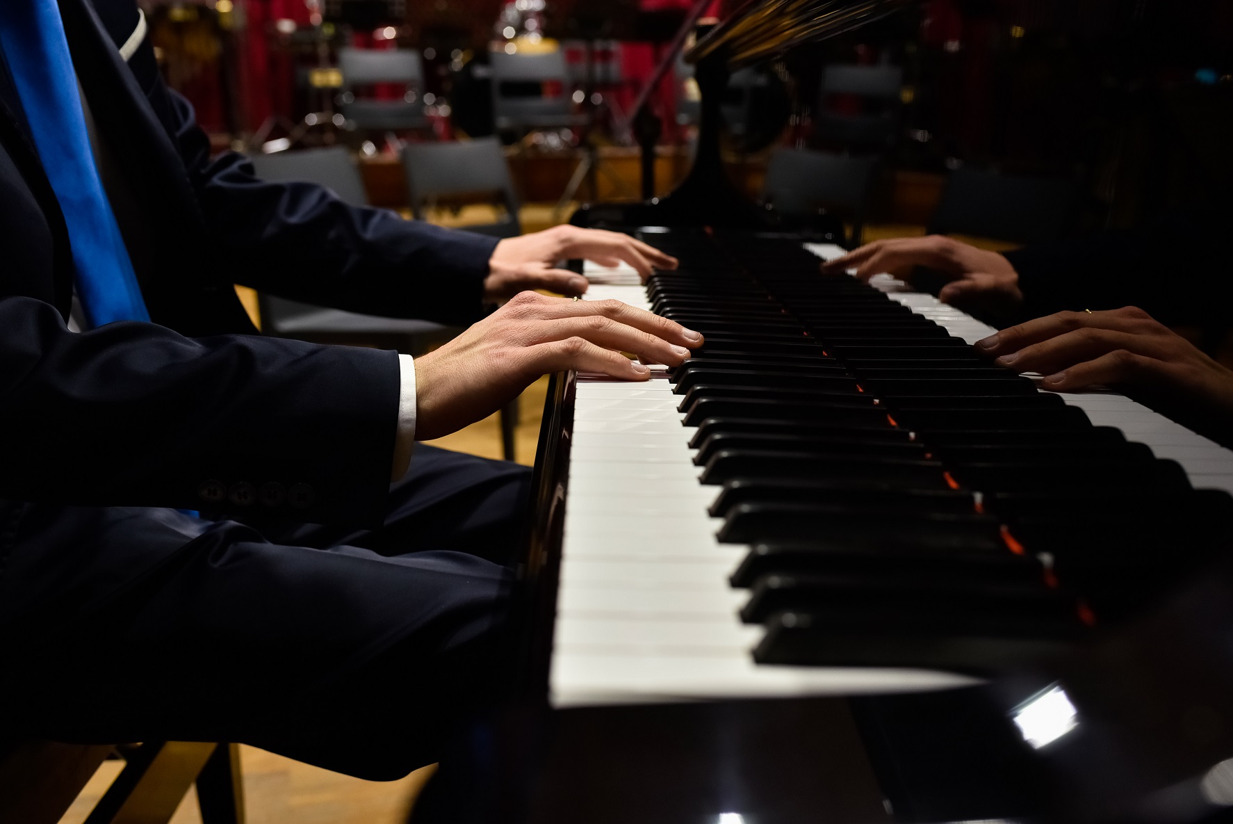 Male pianist playing classical music on a grand piano.