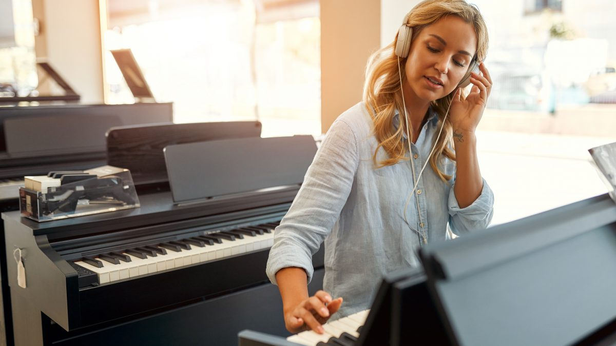 A lady playing a piano in a musical instrument store