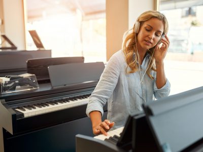 A lady playing a piano in a musical instrument store