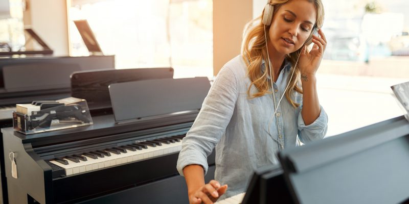 A lady playing a piano in a musical instrument store