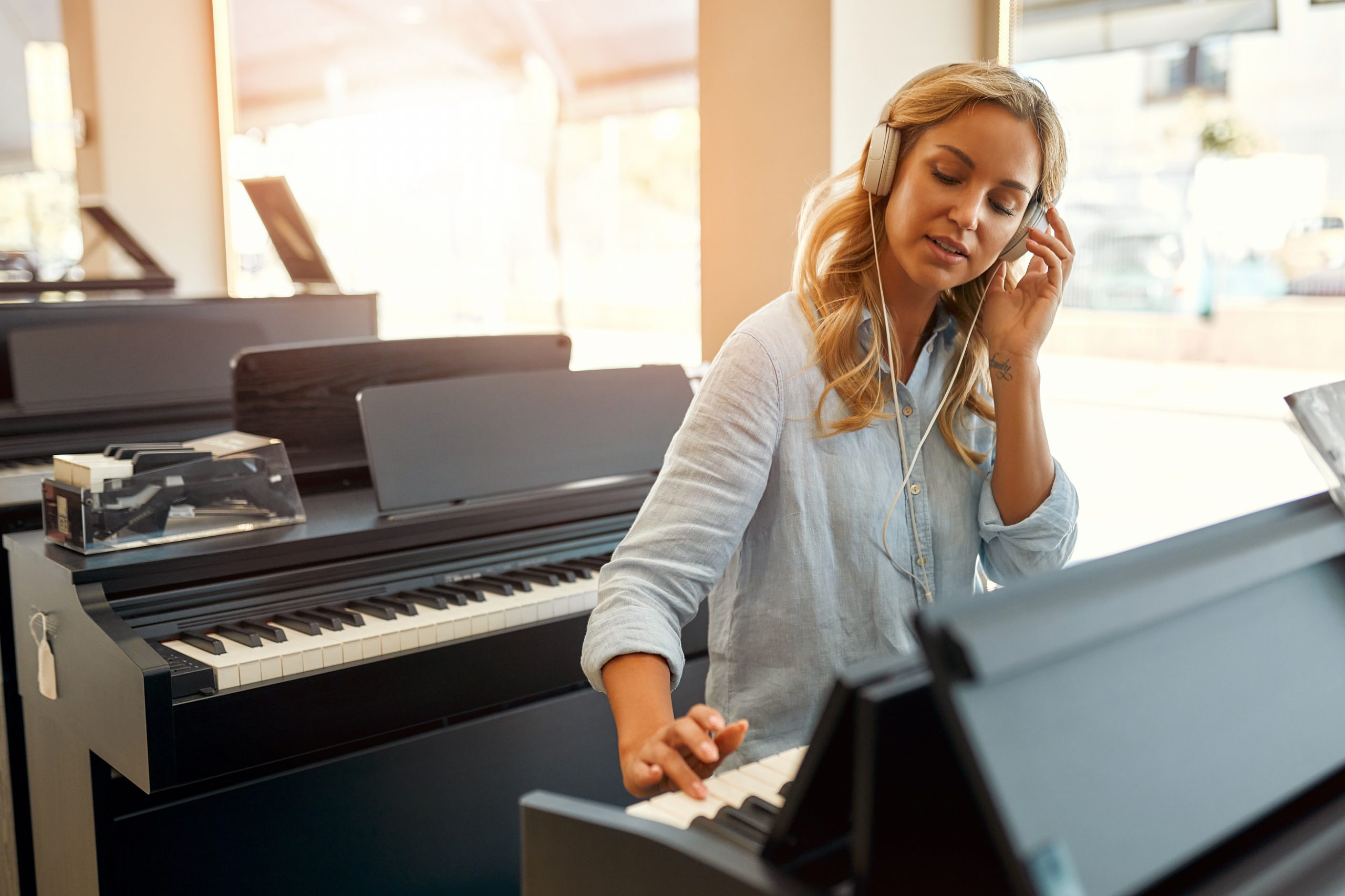 A lady playing a piano in a musical instrument store